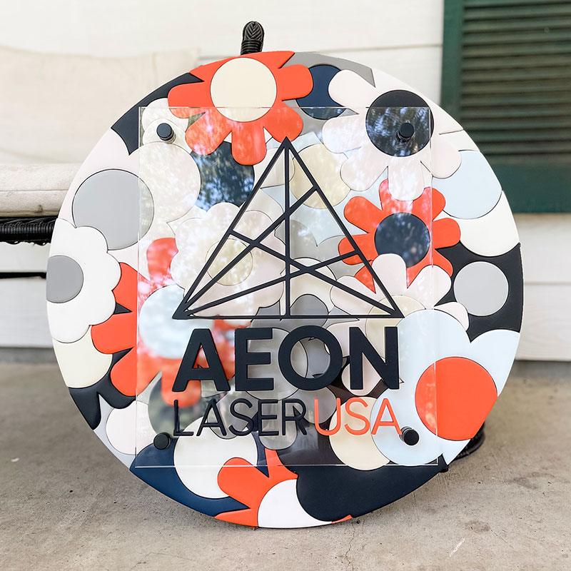 round wooden sign made of orange, blue, and white flowers with a prism and 性高清视频 logo on top