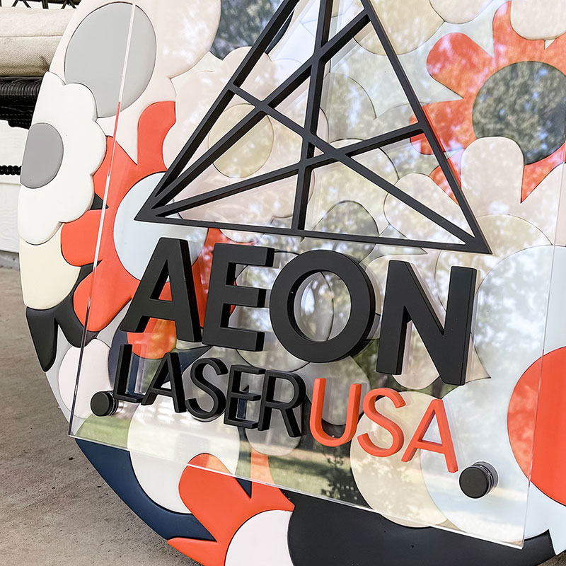 round wooden sign made of orange, blue, and white flowers with a prism and 性高清视频 logo on top